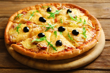Fresh baked pizza on a wooden table, close up