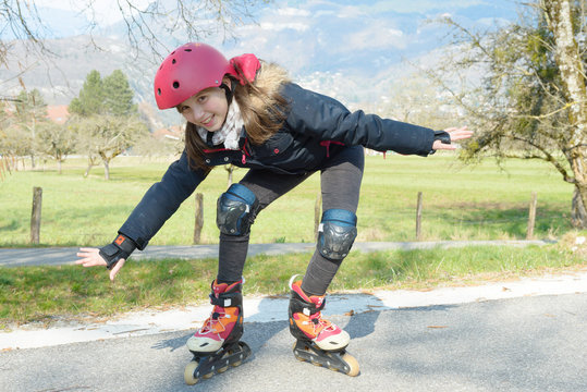 pretty preteen girl on roller skates in helmet at a track