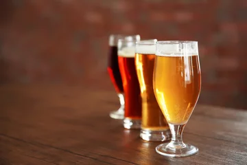 Crédence de cuisine en verre imprimé Bière Verres avec différentes sortes de bière artisanale sur table en bois