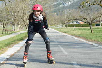 pretty preteen girl on roller skates in helmet at a track