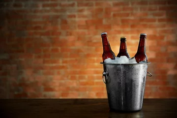 Fotobehang Brown glass bottles of beer in ice-pail on brick wall background © Africa Studio