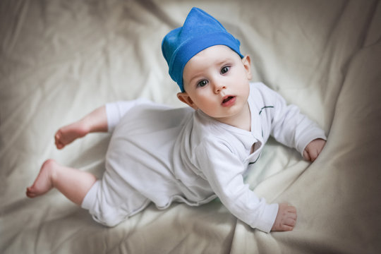Cute 6 month baby with blue hat and smurf costume on beige background