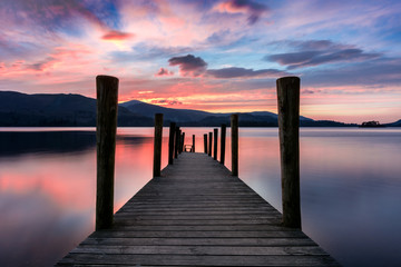 Stunning vibrant pink and purple sunset on a beautiful evening at Ashness Jetty, Derwentwater, Lake District, UK.
