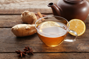 Cup of tea with ginger and cinnamon on wooden background
