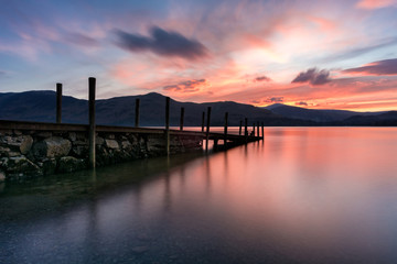 Fototapeta na wymiar Beautiful colourful sunset with a wooden jetty in the Lake District, UK.