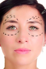 Headshot caucasian woman with dotted lines drawn around eyes looking into camera, preparing cosmetic surgery