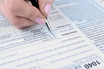 Female hand filling in the Income Tax Form, close up