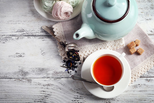Black tea with ceramic utensils and sweets on white wooden table