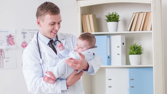 Professional doctor holding toddler in his hands