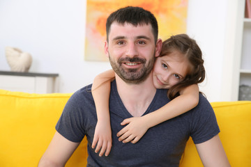 Fototapeta premium Father and daughter sitting on the yellow sofa.