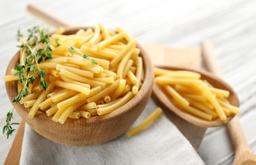 Raw pasta in bowl on wooden table closeup