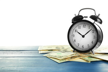 Alarm clock and money on wooden table.