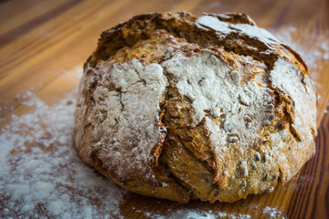 Round bread on the wooden table with flour around