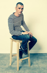 feeling depressed - gloomy young man with striped sweater sitting on a stool expressing depression and emptiness, contrast effects