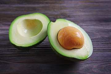 Two halves of fresh avocado on wooden background