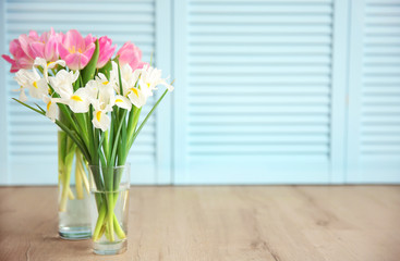 Beautiful fresh tulips and irises on wooden floor against blue doors background