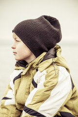 Profile of serious boy in hat and coat