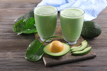 Avocado smoothie with green leaves on wooden background