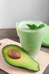 Avocado smoothie with green leaves on grey background
