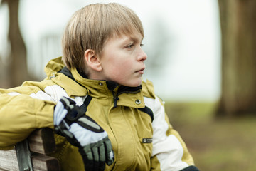Profile of serious boy in coat and gloves