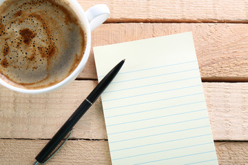 Cup of coffee and blank paper on wooden background