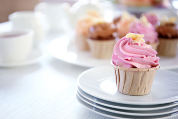 Creamy cupcakes and tea on table closeup