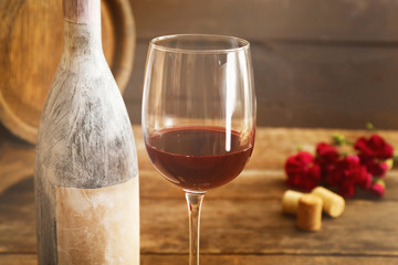 Aged bottle with glass of wine on wooden table