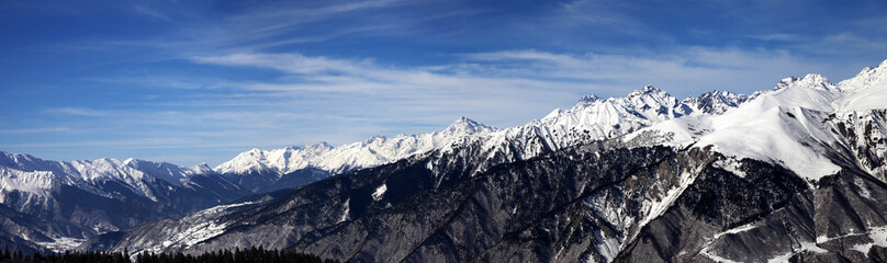 Fototapeta na wymiar Panoramic view on snowy mountains in sun windy day