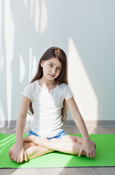 little girl doing gymnastics on a green yoga mat. doing fitness exercise,  on white background. children's fitness, yoga for kids Stock Photo