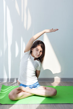 little girl doing gymnastics on a green yoga mat. children's fitness, yoga for kids. doing fitness exercise, on white background. 