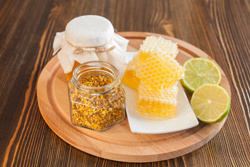 honey in honeycombs, pollen and a lime on a table, selective focus