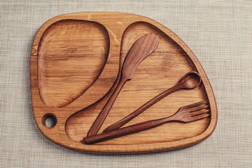 Wooden plate with knife, spoon and fork.