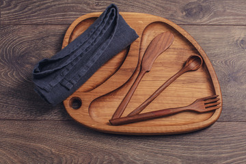 Wooden plate with knife, spoon and fork.