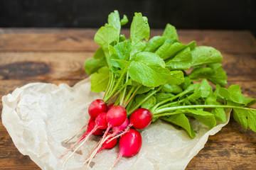 garden radish with a tops of vegetable on a table, selective focus
