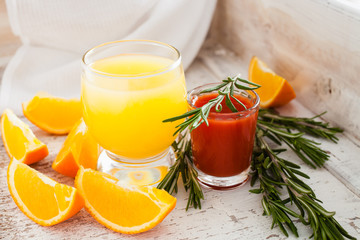 orange and tomato juice on an old shabby background, selective focus