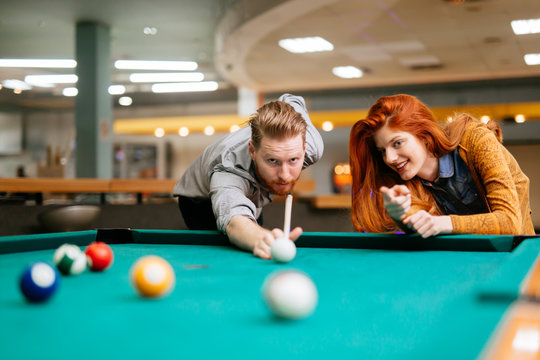 Beautiful couple playing billiards