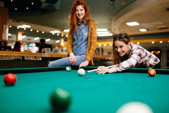 Two female friends playing snooker