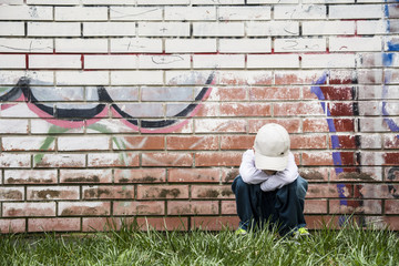 sad boy near brick wall