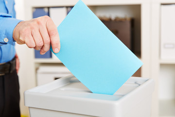 Hand mit Stimmzettel geht wählen