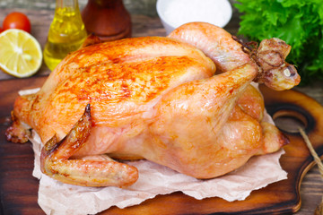 baked chicken with a golden crust with vegetables on a wooden background