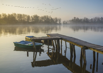 Łódka zacumowana przy drewnianym pomoście w piękny poranek © Mike Mareen