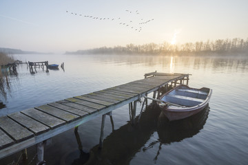 Łódka zacumowana przy drewnianym pomoście w piękny poranek