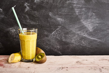 Big glass of yellow fruit smoothie with straw
