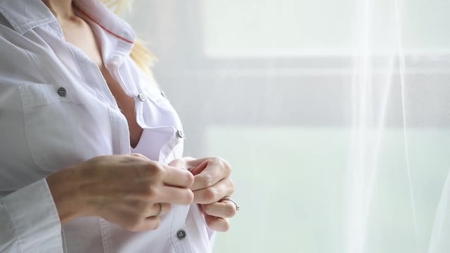 Attractive young pregnant woman unbuttons shirt to expsose belly