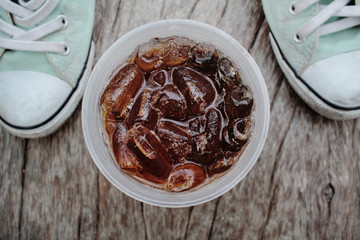 Cola with ice cubes and sneakers