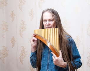 long-haired elderly man with pan flute