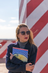 Fashion  girl posing over Red white striped wall background. Beauty woman with pink lips make-up posing on the street.