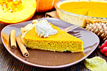 Pie pumpkin in brown plate with cream on board