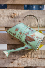 Details. Vintage metallic watering can by a wooden background. Old rustic watering can on the wooden wall.