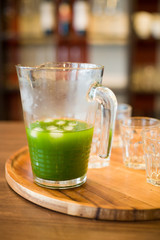 Healthy organic spinach, kale, green apple and celery smoothie with ice on wooden background. Summer drinks. Jar of spinach juice on wooden table, closeup